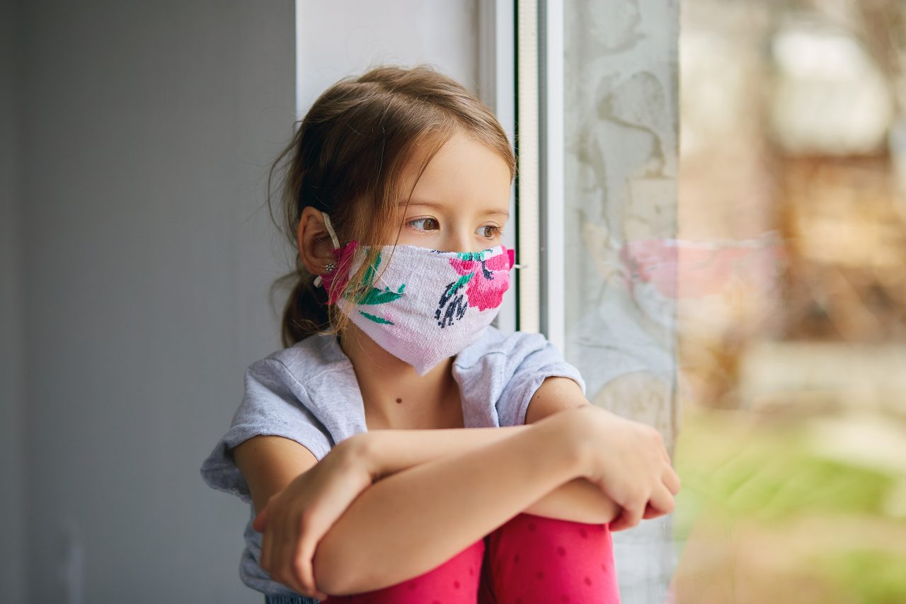 little-girl-child-in-mask-sits-on-windows-coronavi-TDPEMHW-1280x853.jpg